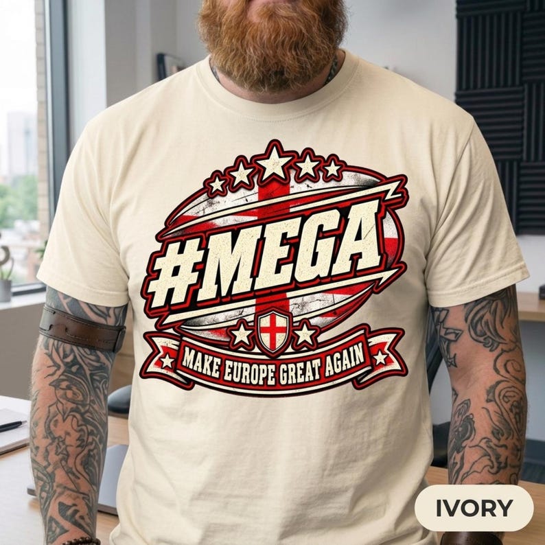 Close-up of the "#MEGA Make Europe Great Again" England T-shirt by SarcasmArt in Ivory worn by a bearded man, showing the St George cross badge.