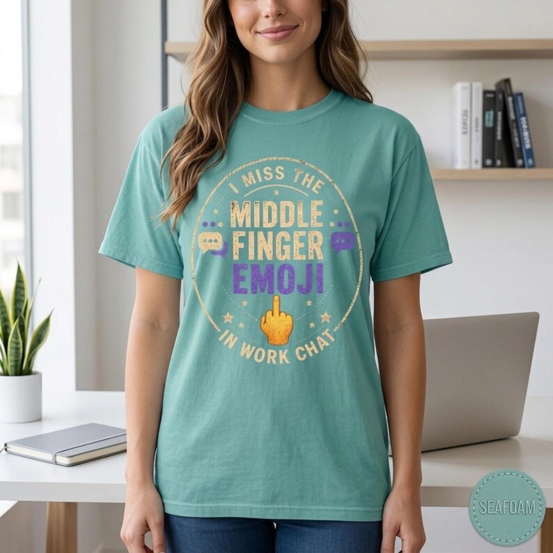 Woman in a bright office wearing the "I Miss the Middle Finger Emoji in Work Chat" sarcastic office T-shirt by SarcasmArt in Seafoam.