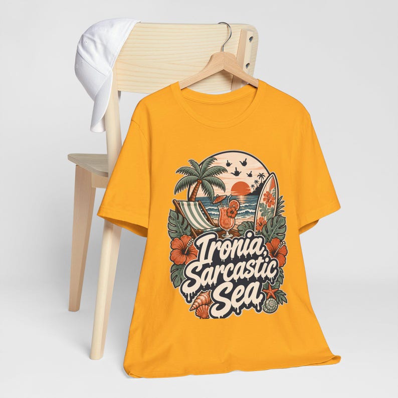 The "Ironia, Sarcastic Sea" retro beach T-shirt by SarcasmArt in golden yellow hanging on a wooden chair.