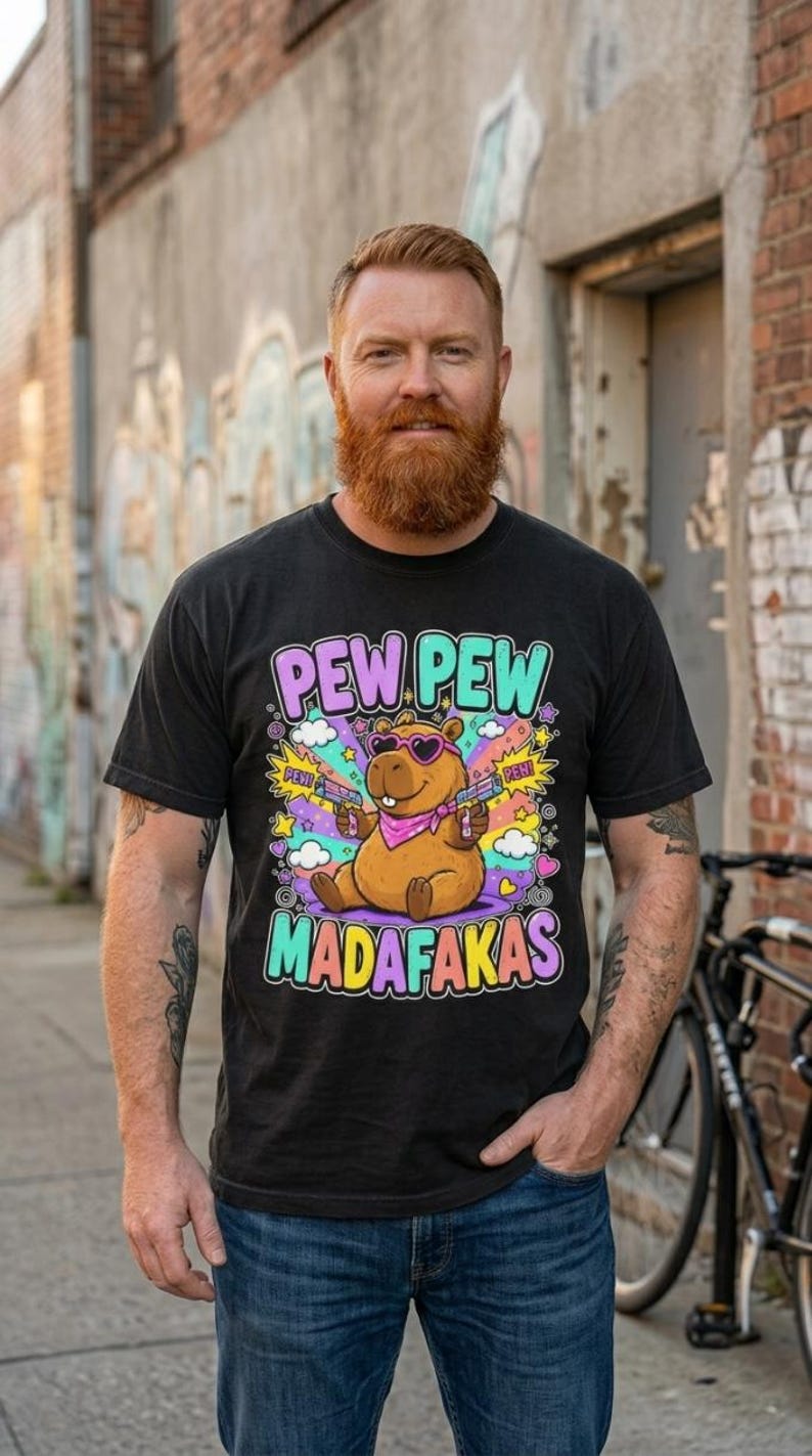 Bearded man on an urban street wearing the "Pew Pew Madafakas" capybara meme T-shirt by SarcasmArt in Black.