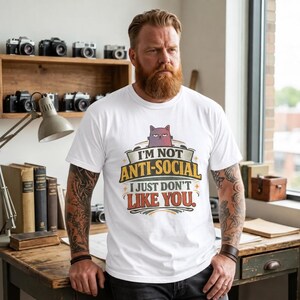 Bearded man in a cozy study wearing the "I'm Not Anti-Social, I Just Don't Like You" sarcastic introvert T-shirt by SarcasmArt in White.
