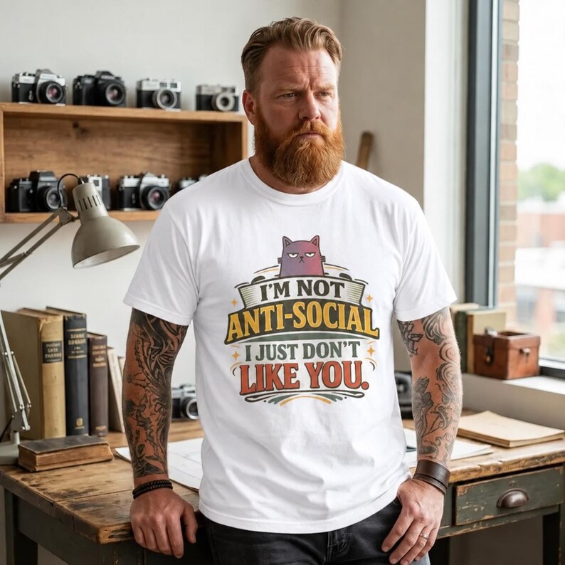 Bearded man in a cozy study wearing the "I'm Not Anti-Social, I Just Don't Like You" sarcastic introvert T-shirt by SarcasmArt in White.