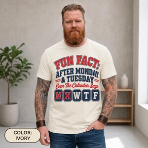 Bearded man wearing the "Fun Fact: After Monday & Tuesday" WTF varsity work T-shirt by SarcasmArt in Ivory, showing the red and navy varsity print.