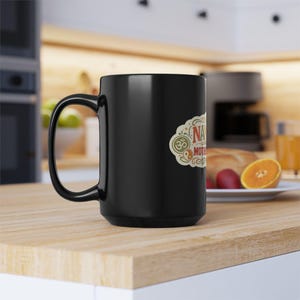 Handle view of the black "Namaste Motherfuckers" funny yoga coffee mug by SarcasmArt on a kitchen counter – adult spiritual humor for your morning coffee.