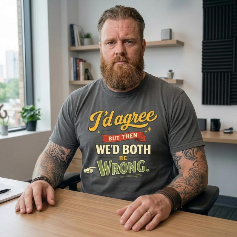 Bearded man sitting at a desk wearing the "I'd Agree With You But Then We'd Both Be Wrong" sarcastic quote T-shirt by SarcasmArt in Pepper, a funny office humor shirt.