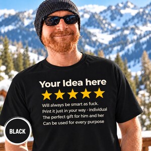 Bearded man in a beanie and sunglasses in front of snowy mountains wearing the personalized golden 5-star review T-shirt by SarcasmArt in Black, with your custom title, five golden stars and four lines of your own review text in white.