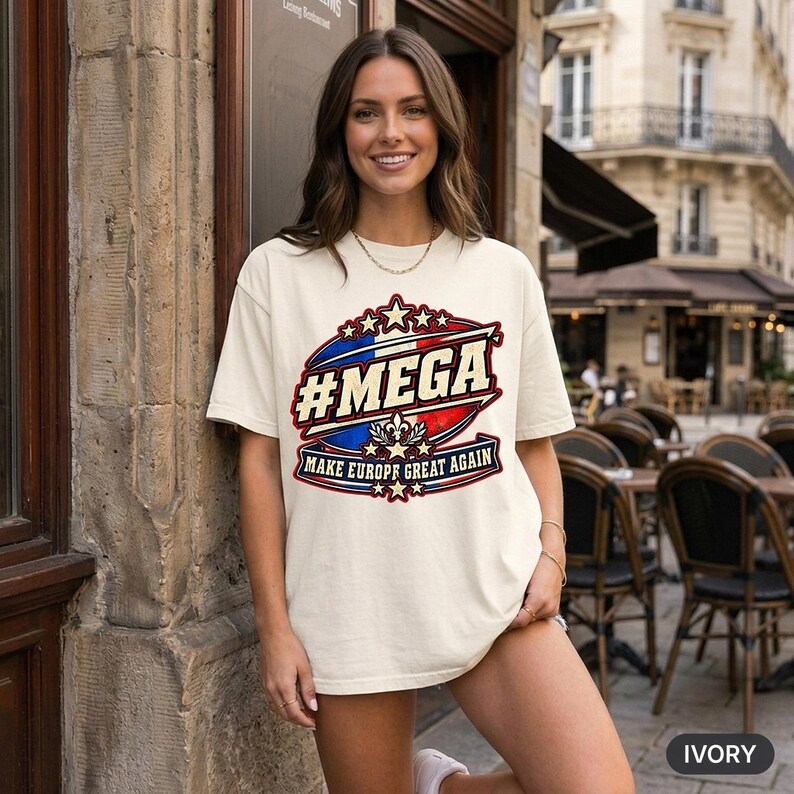 Smiling woman at a European street café wearing the "#MEGA Make Europe Great Again" France T-shirt by SarcasmArt in Ivory.