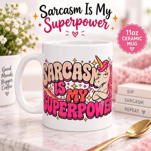 "Sarcasm Is My Superpower" unicorn coffee mug by SarcasmArt: white 11 oz glossy ceramic mug with an eye-rolling retro unicorn with a pink mane and bold pink and cream lettering SARCASM IS MY SUPERPOWER, on a pink desk.
