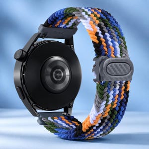 Puede incluir: Un reloj inteligente negro con caja circular y correa elástica trenzada con un patrón multicolor de hilos azules, naranjas, verdes, blancos y negros, asegurado por una hebilla deslizante ajustable de color gris oscuro con textura de carbono.
