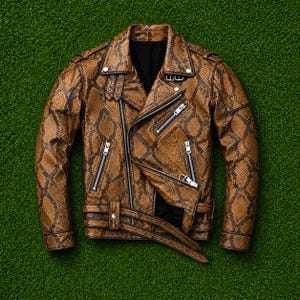 May include: A brown and black snakeskin-patterned motorcycle jacket featuring a notched lapel, silver-tone metal zips on the front and sleeves, a buckled waist belt, shoulder epaulettes, and a black interior lining with a structured collar.