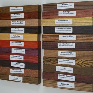 May include: A collection of labelled wood samples, displaying a variety of colours and grain textures. The samples range from pale yellow to rich reds and dark browns. Each sample is identified with its wood type and a website address.