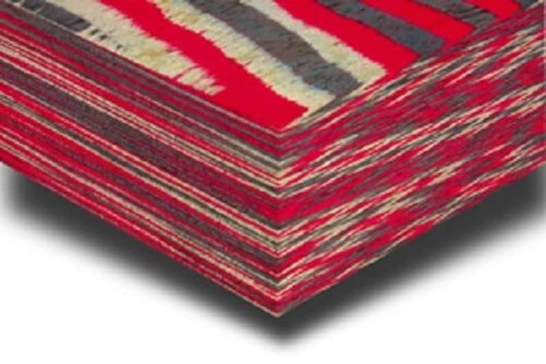 May include: A stack of folded textiles featuring a bold striped design in red, grey, and cream. The fabric has a woven texture. The edges are precisely aligned, forming a neat, geometric shape. The colour palette is striking.