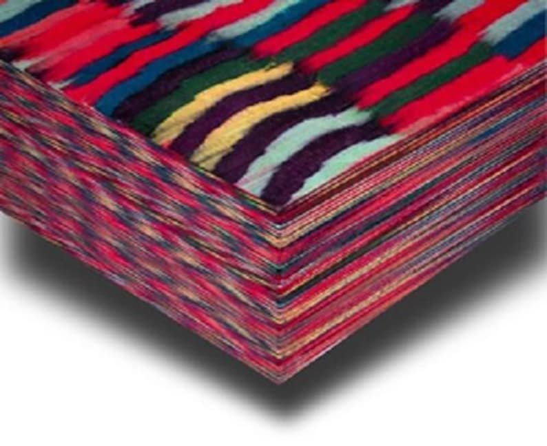 May include: A stack of patterned fabric with a colourful, abstract design. The top layer has bold, brushstroke-like stripes in red, blue, green, yellow, and purple. The edges of the fabric are a mix of red, pink, and other colours.