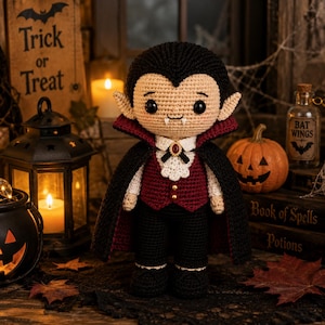 May include: A crocheted vampire doll with black hair, pale skin, and two white fangs. The doll wears a black cape with a dark red lining, a white collared shirt with a ruffled jabot, a dark red vest with two gold buttons, and black trousers.