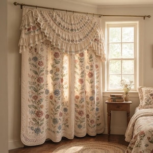 May include: A cream-coloured quilted curtain set featuring a floral pattern with red, blue, and green botanical motifs. The curtains include a ruffled valance with a semi-circular design, hanging from a brass rod over a window.