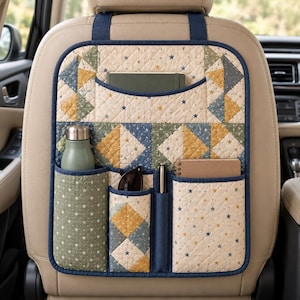 May include: A quilted car seat back organizer featuring a star pattern in cream, blue, green, and yellow. It includes a large top pocket and four lower pockets holding a water bottle, sunglasses, a pen, and two notebooks.