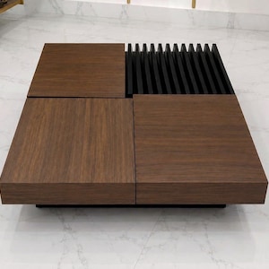Könnte beinhalten: Ein quadratischer Couchtisch mit drei glatten, dunkelbraunen Holzmaserungsplatten und einem Abschnitt aus vertikalen schwarzen Lamellen. Der Tisch hat ein flaches Design mit einer ebenen Oberfläche, die Holztexturen mit Lamellenelementen kombiniert.