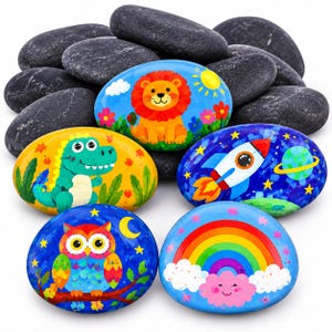 May include: A collection of smooth, oval-shaped river stones, with five painted in vibrant colors featuring a lion, a green dinosaur, a space rocket, an owl, and a rainbow with a cloud, surrounded by several plain black stones.