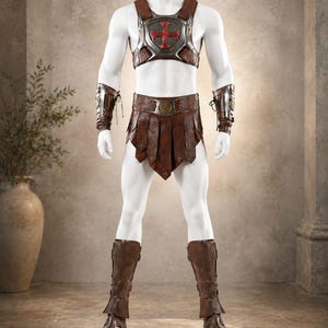 May include: A brown leather gladiator-style costume set featuring a chest plate with a central red cross emblem, a matching waist belt with hanging panels, two forearm bracers, and a pair of tall brown leather boots with lace-up detailing.