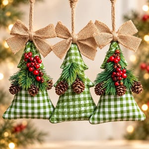 May include: Three hanging ornaments shaped like Christmas trees, crafted from green and white checkered fabric. Each ornament features a burlap bow at the top, a cluster of red berries, green pine needles, and small brown pinecones attached.
