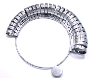 May include: A silver ring sizer with a metal ring for each size from 4 to 14. The rings are arranged in a circle on a metal stand.