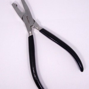 May include: Black handled pliers with silver jaws for crimping jewelry findings. The pliers have the text "Beadsmith" printed on the side.