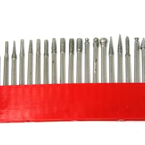 May include: A set of 20 diamond-tipped rotary tool bits in a red plastic holder. The bits are arranged in a row and are all the same size. They are used for grinding, sanding, and polishing.