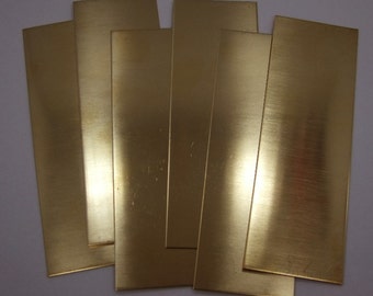 May include: Six rectangular sheets of polished brass, stacked in a fan shape. The sheets are a bright gold color and have a smooth, reflective surface.