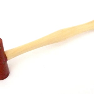 May include: A wooden mallet with a brown leather head. The mallet has a smooth wooden handle.