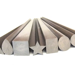 Op de afbeelding: Een set van acht metalen staven met verschillende dwarsdoorsneden, waaronder een driehoek, een traan, een vierkant, een ster, een rechthoek, een cirkel, een hart en een hartvorm. De staven zijn allemaal even lang en zijn in een rij gerangschikt.