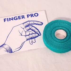 Puede incluir: Un rollo de cinta deportiva turquesa con las palabras "Finger Pro" impresas en una tarjeta blanca con una ilustración azul de una mano.