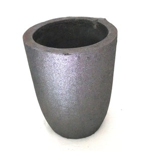 May include: A gray ceramic crucible, a type of container used for melting metals.