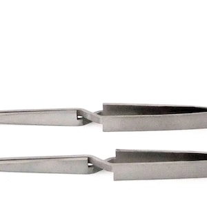 May include: Two pairs of stainless steel tweezers with angled tips. The tweezers are closed and lying flat on a white surface.