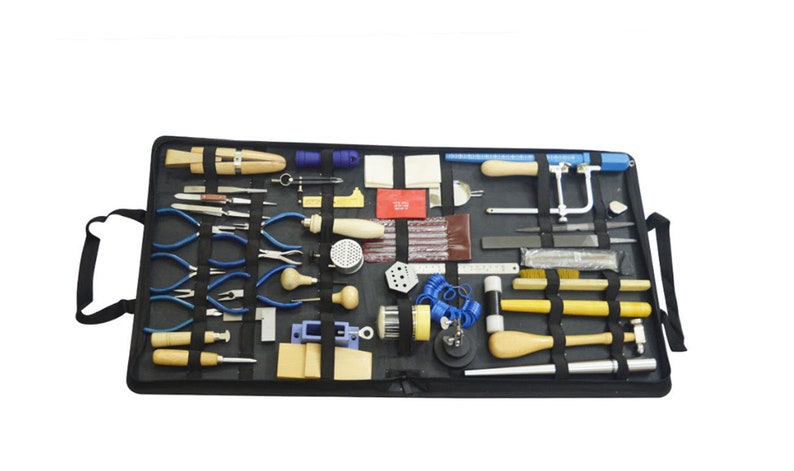 May include: A black carrying case containing a selection of jewellery making tools, including pliers, cutters, hammers, files, and a saw. The tools are arranged in rows and secured with elastic straps.