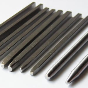 May include: A white ceramic mug with a black handle and the text "But First, Coffee" in a bold, black font. The mug is set against a blurred background, suggesting a cozy setting. The mug appears to be approximately 4 inches tall.