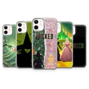 May include: Five clear phone cases featuring Wicked-themed designs. The cases display green and pink color schemes, silhouettes of witches, a yellow brick road, the Emerald City, and the word WICKED printed in various fonts across the back surfaces.