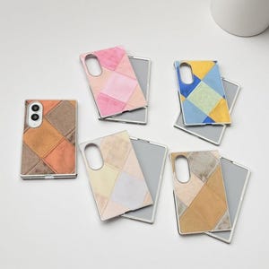 May include: Five rectangular phone cases featuring a patchwork diamond pattern in various colour combinations including pink, blue, yellow, brown, and tan. Each case has a cutout for a camera lens and a smooth, matte-textured surface finish.