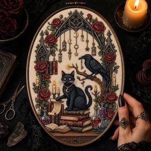May include: An oval cross-stitch embroidery in a wooden hoop featuring a black cat sitting on a stack of books, a raven on a branch holding a key, red roses, hanging moon charms, candles, and glass potion bottles on a cream fabric background.