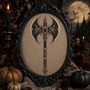 May include: A cross-stitch embroidery of a double-bladed battle axe featuring black, gold, and red thread on a tan fabric background, encased in an ornate, oval-shaped black frame with intricate scrollwork detailing along the outer edges.