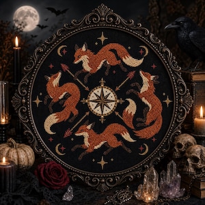 May include: A circular cross-stitch embroidery featuring four orange foxes arranged in a radial pattern around a central compass rose design. The foxes are stitched on a black fabric background, framed within an ornate, dark metallic circular frame.