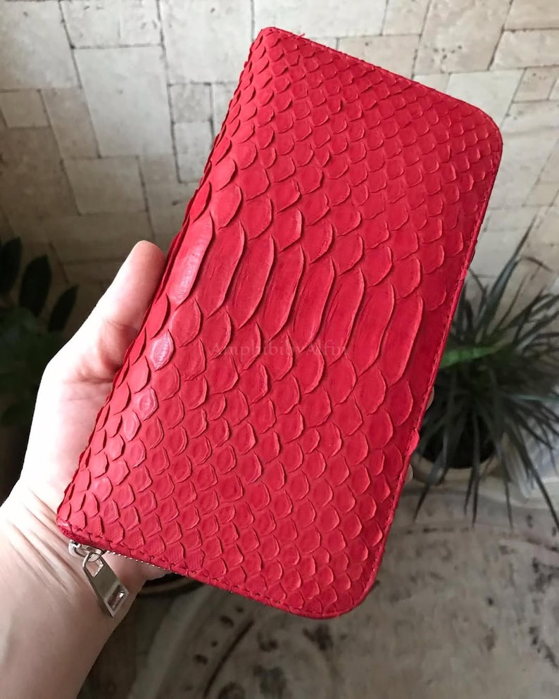 Peut inclure: Un portefeuille rectangulaire rouge vif pr&eacute;sentant un motif textur&eacute; en peau de serpent sur toute la surface ext&eacute;rieure. Le portefeuille est s&eacute;curis&eacute; par une tirette de fermeture &eacute;clair en m&eacute;tal argent&eacute; situ&eacute;e dans le coin inf&eacute;rieur.
