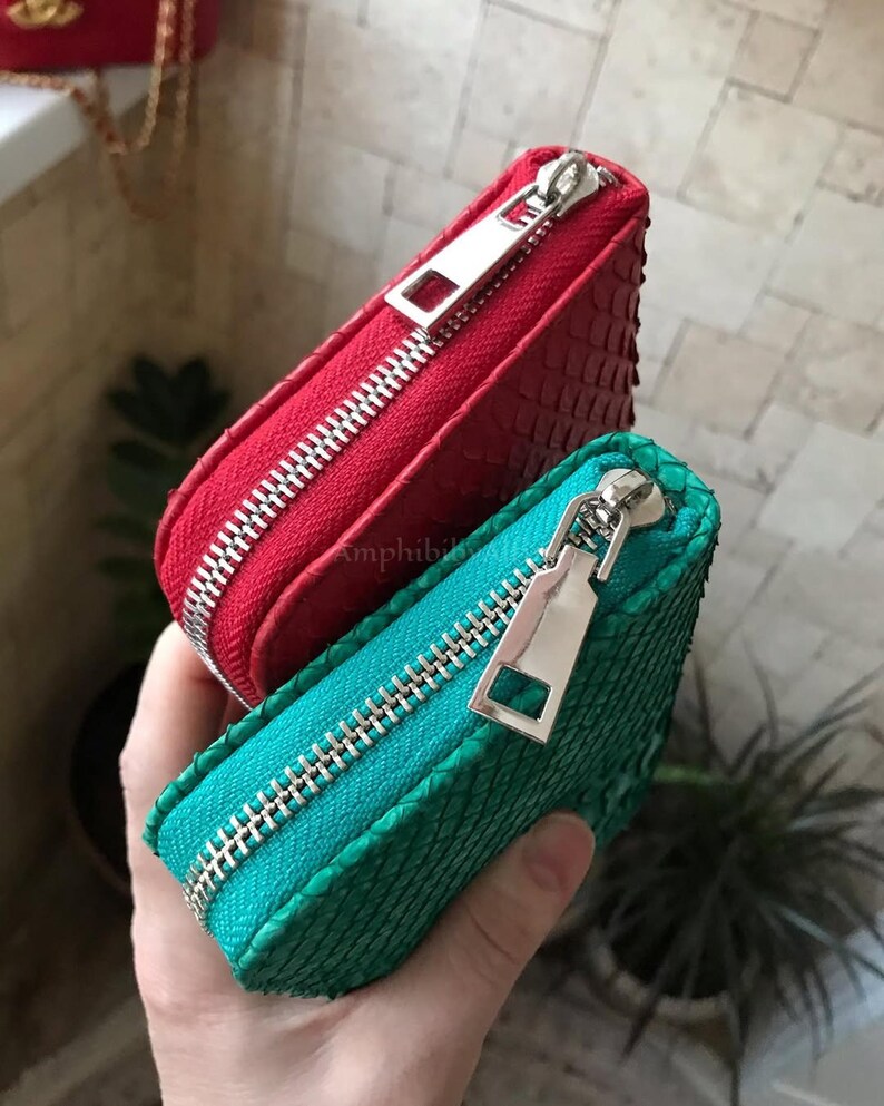 Peut inclure: Deux petites pochettes rectangulaires &agrave; fermeture &eacute;clair, l'une rouge vif et l'autre bleu sarcelle, pr&eacute;sentant toutes deux une texture en relief semblable &agrave; des &eacute;cailles. Chaque pochette est dot&eacute;e d'une tirette en m&eacute;tal argent&eacute;.