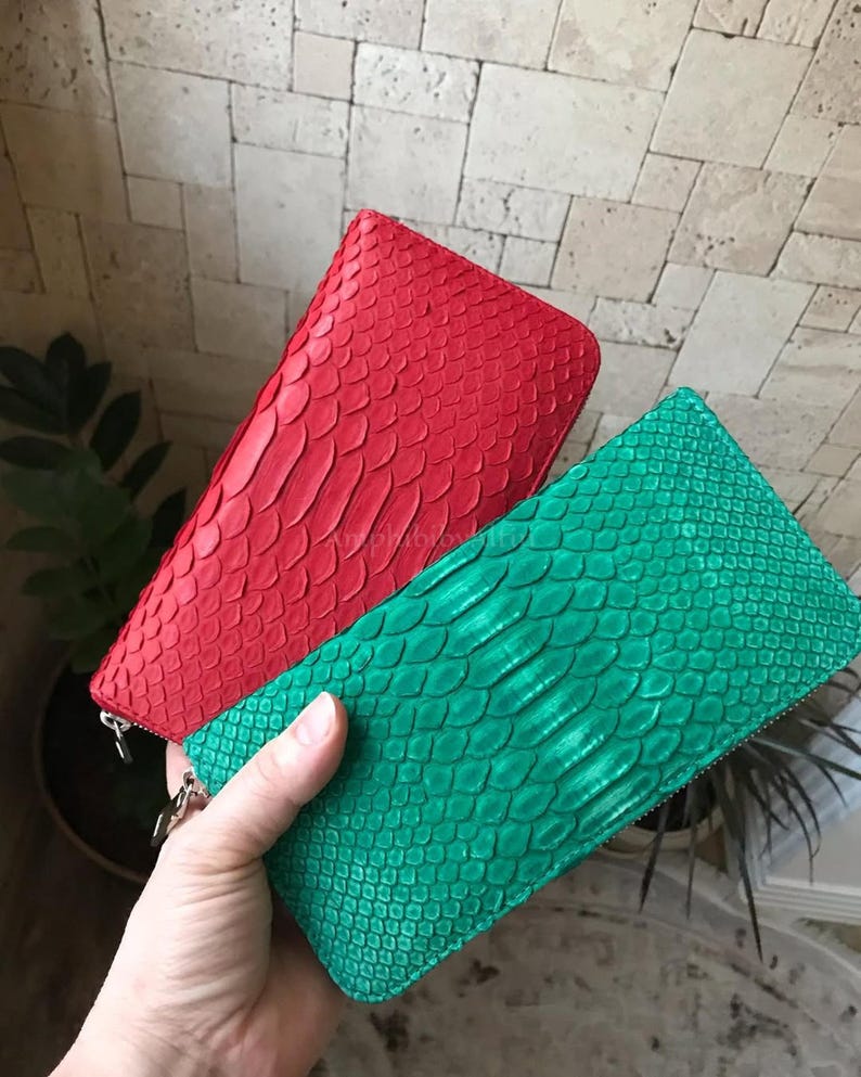 Peut inclure: Deux portefeuilles rectangulaires &agrave; fermeture &eacute;clair avec un motif textur&eacute; en peau de serpent. L'un est rouge vif et l'autre est vert &eacute;meraude &eacute;clatant. Les deux articles poss&egrave;dent une fermeture &eacute;clair m&eacute;tallique sur le dessus et le c&ocirc;t&eacute;.