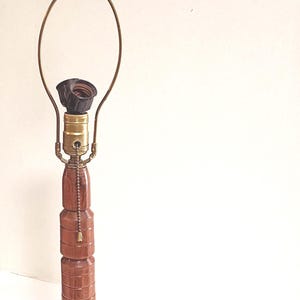 May include: A vintage wooden table lamp with a stacked column design. The lamp features a brass neck and a round base. The lamp is approximately 28 inches tall.