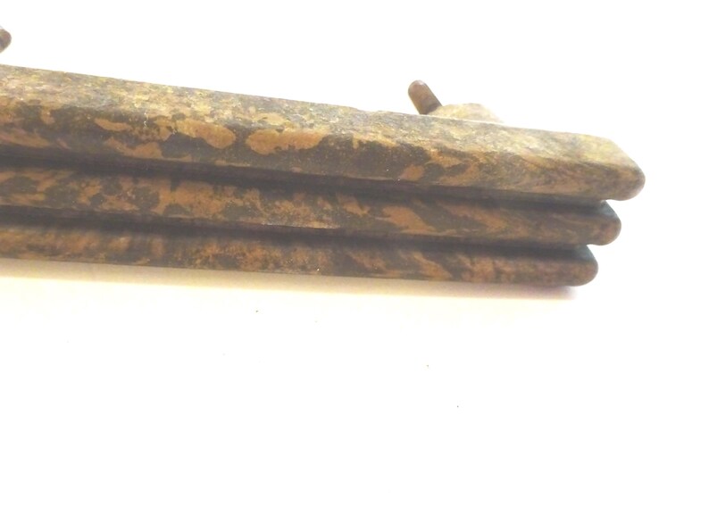May include: Close-up of a stack of three weathered, rectangular wooden planks. The planks have a mottled brown and tan pattern, with a rough, textured surface. A small, rounded wooden peg is visible on the top plank.