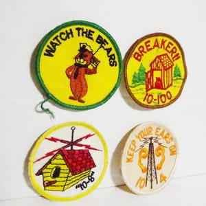 May include: Four vintage embroidered patches with cartoon graphics. One patch says "Watch the Bears" with a bear character. Another says "Breaker 10-100" with a cabin graphic. The third says "10-8" with a house graphic. The last says "Keep Your Ears On 10-4".