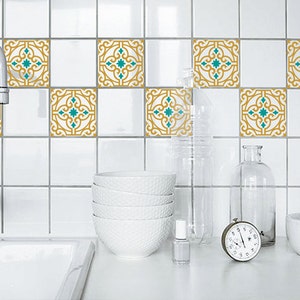 May include: White kitchen tiles with a repeating pattern of gold and teal decorative squares. A white sink, faucet, and various kitchen accessories, including bowls, bottles, and a timer, are visible.