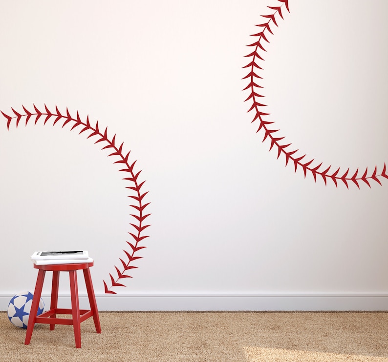 Puede incluir: Dos calcoman&iacute;as rojas de puntadas de b&eacute;isbol en una pared blanca. Las puntadas tienen la forma de una costura de b&eacute;isbol.