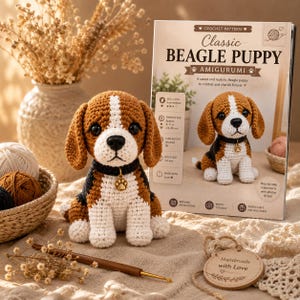 Peut inclure: Un chiot beagle amigurumi au crochet en fil marron, blanc et noir, doté d'un collier noir avec une breloque patte dorée. À côté se trouve un livret de modèle imprimé intitulé Classic BEAGLE PUPPY AMIGURUMI avec une photo du jouet.