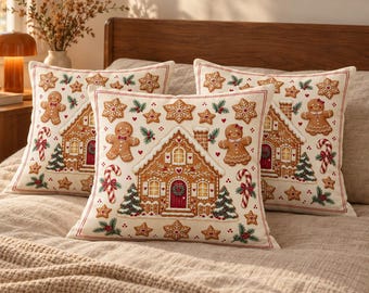 May include: Three square throw pillows with an off-white background featuring a repeating pattern of gingerbread houses, gingerbread people, candy canes, evergreen trees, and star-shaped cookies with red and green accents.